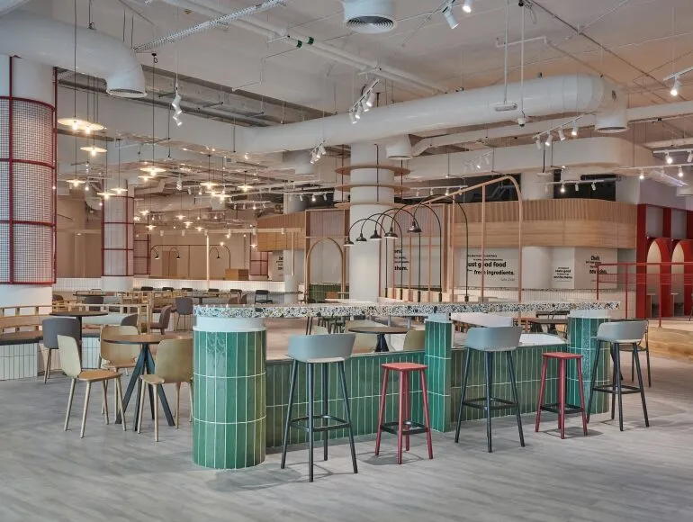 Contemporary sustainable dining area at Picnic Square in Dubai featuring natural materials, open ceilings, and mixed seating designed by Summertown Interiors.