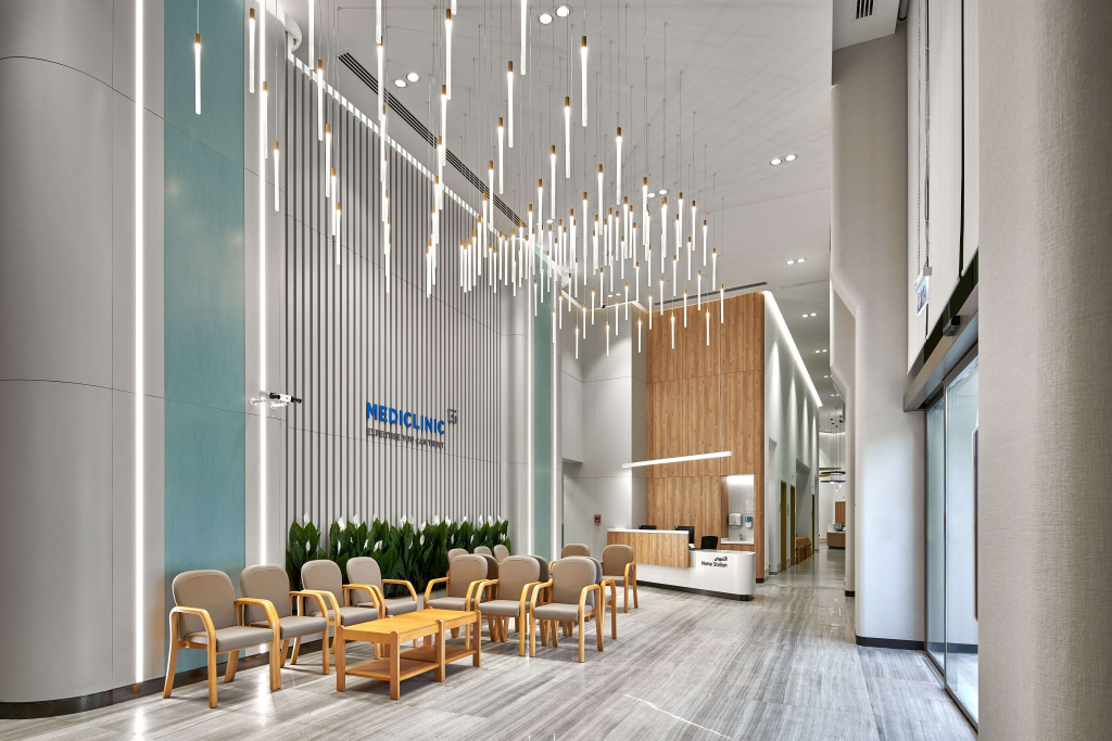 Modern medical clinic reception with soft seating, vertical acoustic panels, indoor greenery, and sculptural pendant lighting at Mediclinic Dubai Creek Harbour.
