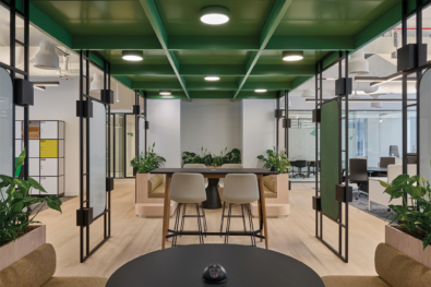 Contemporary open-plan breakout area with green ceiling detail, biophilic elements, and collaborative seating at Schneider Electric’s Dubai office – Summertown Interiors fit-out.