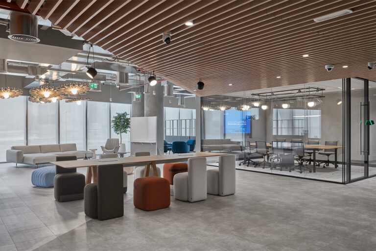 WELL-certified office fit-out in Dubai by Summertown Interiors, featuring timber slatted ceiling, collaborative seating, and glass-partitioned meeting room