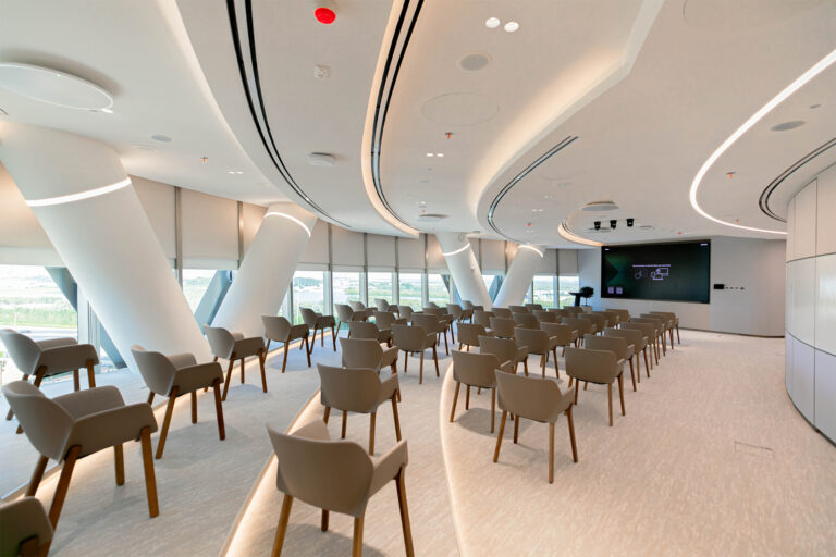 Modern conference room at Abu Dhabi Investment Council's Al Bahr Tower office featuring contemporary seating, integrated AV technology, natural daylight, and sustainable workplace design by Summertown Interiors.