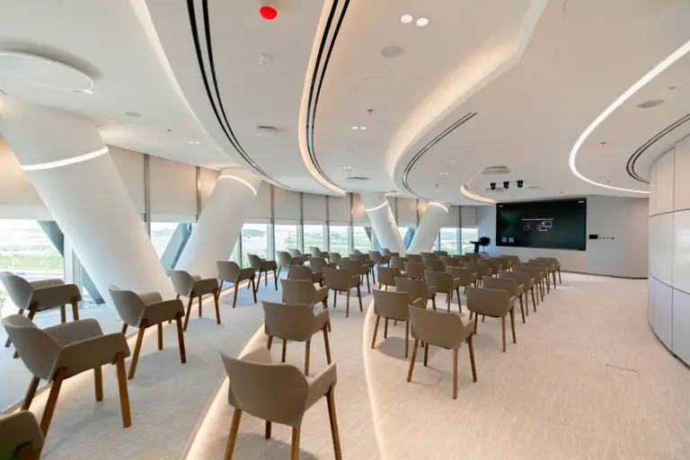 Modern conference room at Abu Dhabi Investment Council's Al Bahr Tower office featuring contemporary seating, integrated AV technology, natural daylight, and sustainable workplace design by Summertown Interiors.